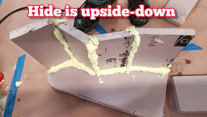 Attach the hide to the background using spray foam and carve it to look like rock.