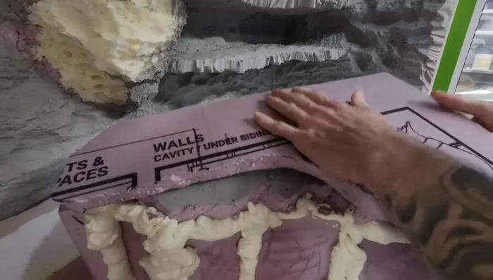 Attach the hide to the background using spray foam and carve it to look like rock.