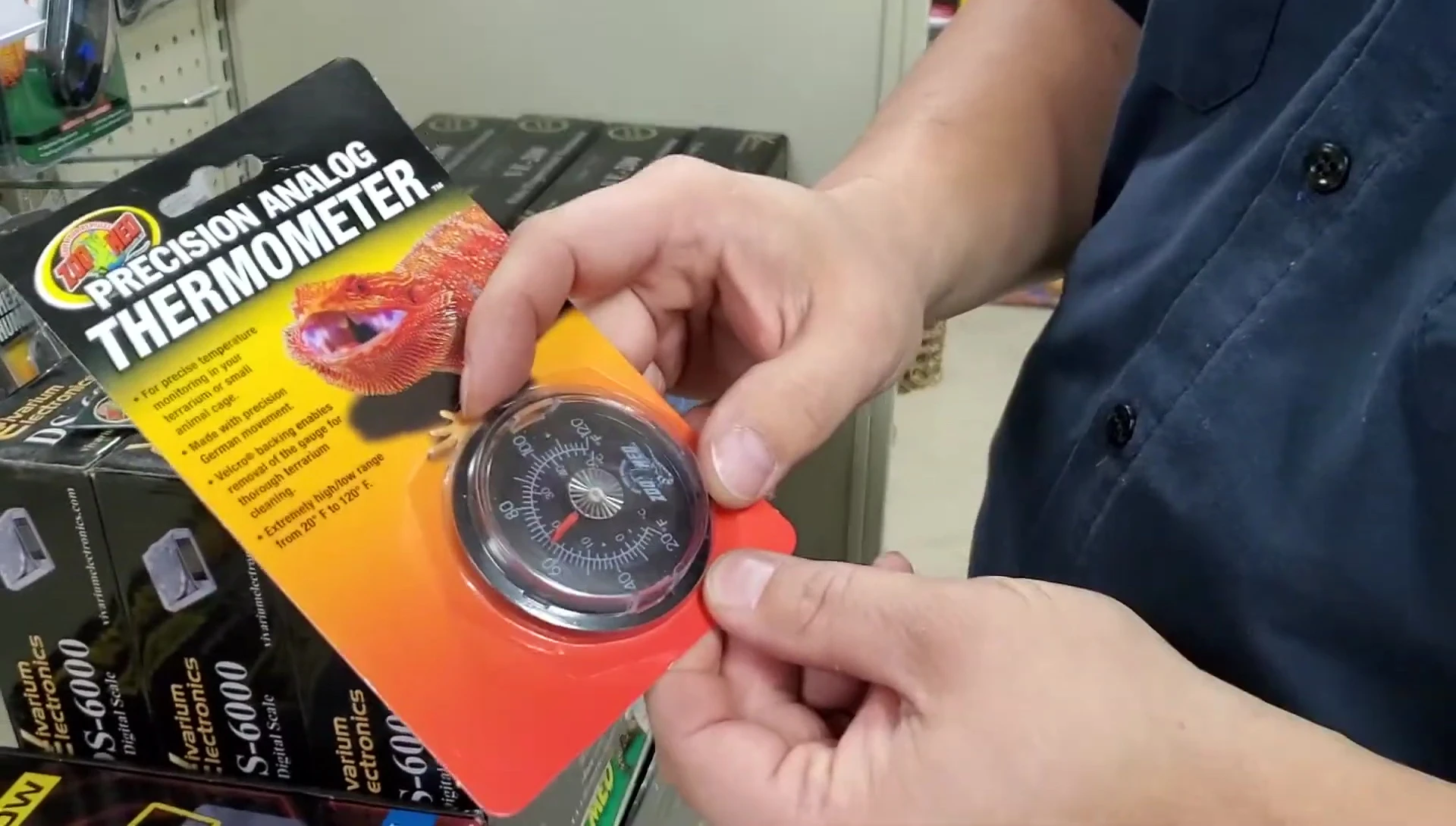 Hand holding an analog thermometer showing the dial.