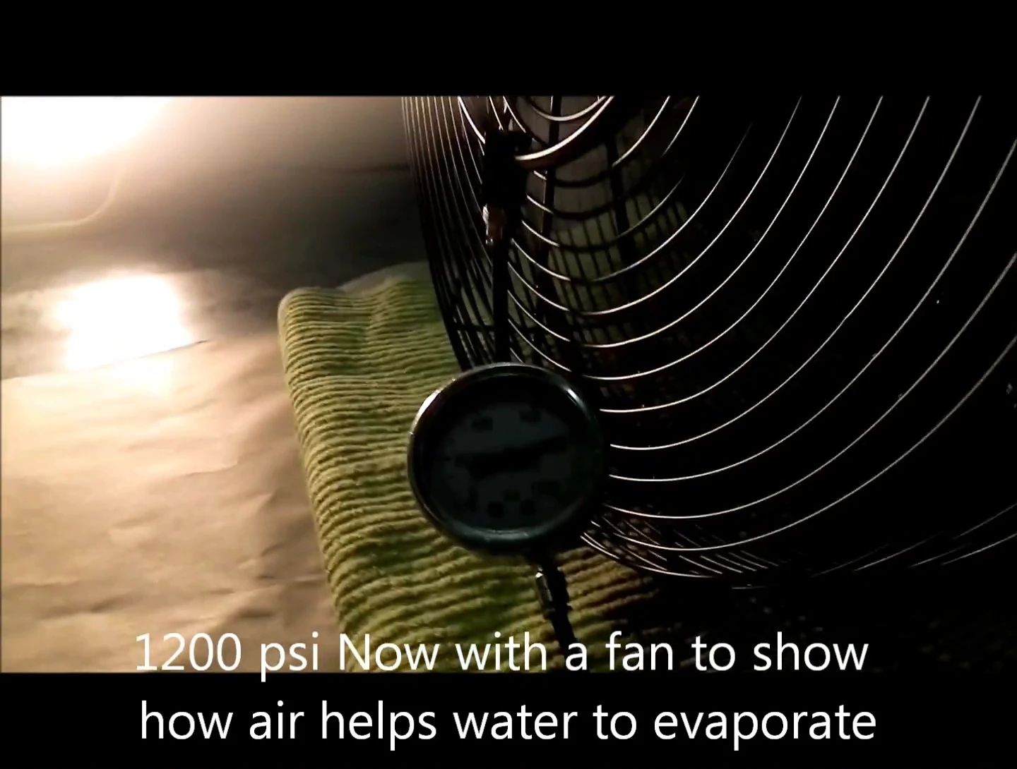A glass plate is held under the 1200 PSI mist to show evaporation.
