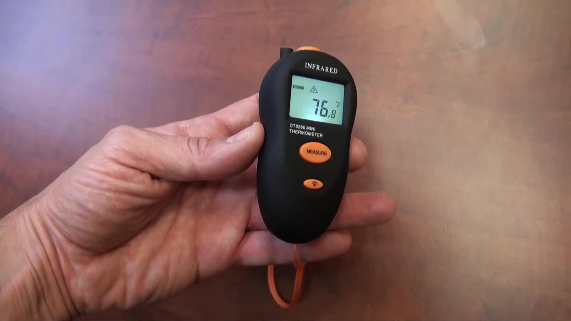 Close-up of the thermometer in hand, showcasing the ergonomic design.