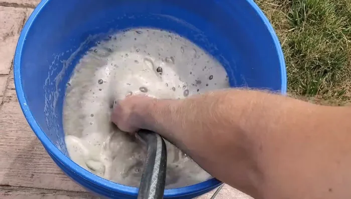 Carefully siphon or remove the dirty water from the top of the bucket, leaving the sand behind.